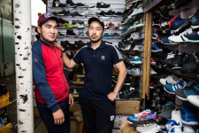 Azim (right) with a a friend at his shoe kiosk in a Bishkek market.