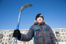 A young boy standing tall on the ice hockey rink.